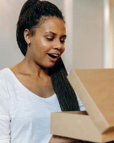 Une femme découvre avec émerveillement le contenu d'une boite