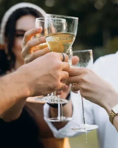 Gros plan sur les mains de trois personnes avec un verre de vin et qui trinquent